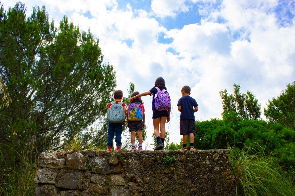 bambini su muretto nel verde